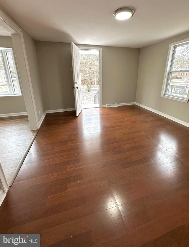 empty room featuring dark hardwood / wood-style flooring and a healthy amount of sunlight