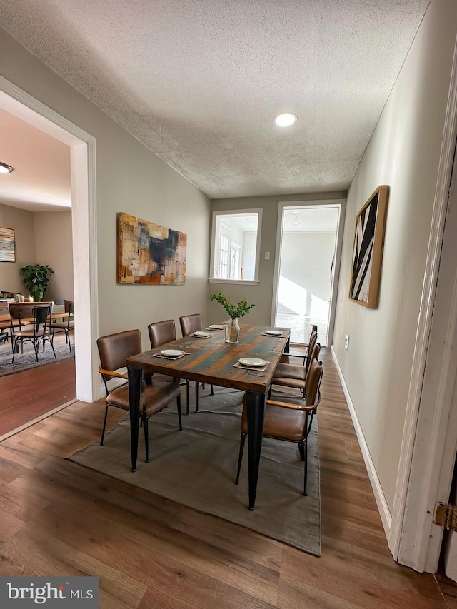 dining space with dark hardwood / wood-style floors and a textured ceiling