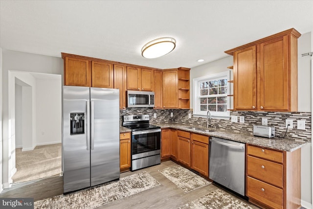 kitchen with decorative backsplash, sink, stainless steel appliances, and stone countertops