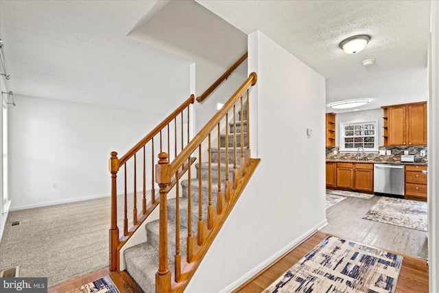 stairway featuring sink, wood-type flooring, and a textured ceiling