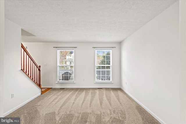 carpeted spare room with a textured ceiling