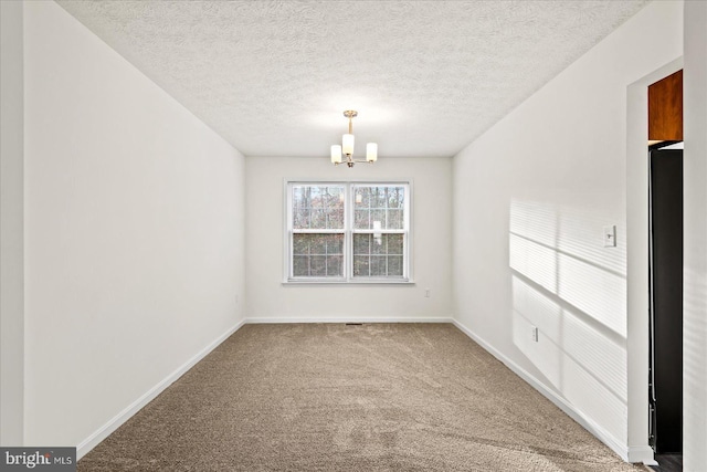 carpeted spare room featuring a textured ceiling and an inviting chandelier