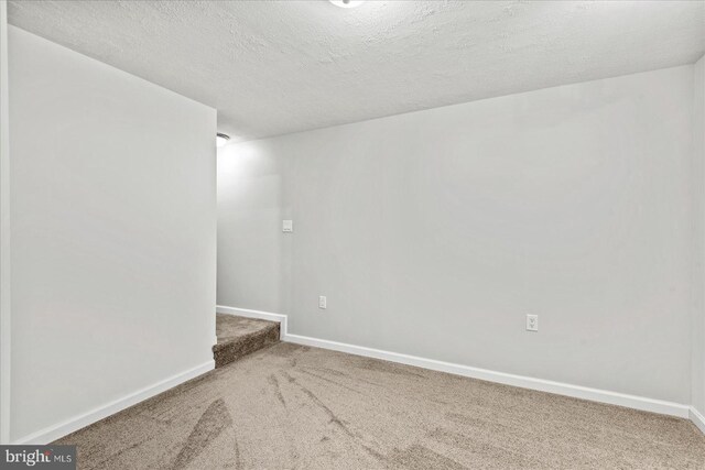 carpeted spare room featuring a textured ceiling