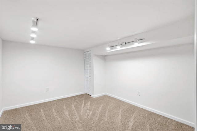 basement with carpet flooring and rail lighting