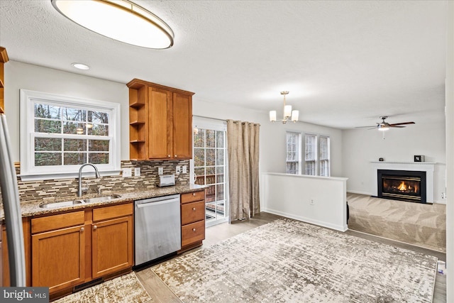 kitchen featuring decorative backsplash, light stone countertops, light wood-type flooring, sink, and dishwasher