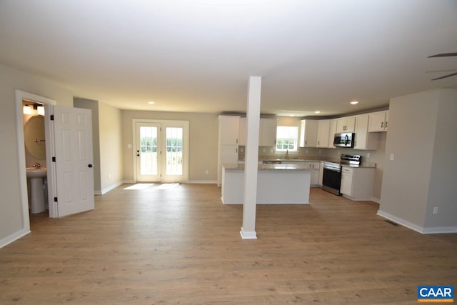 kitchen with white cabinetry, french doors, stainless steel appliances, light hardwood / wood-style floors, and decorative backsplash