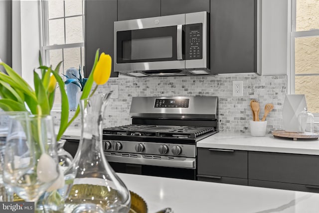 kitchen with light countertops, stainless steel appliances, backsplash, and gray cabinetry