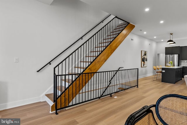 stairway featuring baseboards, wood finished floors, and recessed lighting