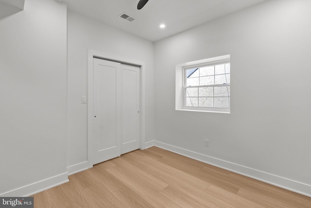 unfurnished bedroom featuring light wood finished floors, baseboards, visible vents, and a closet