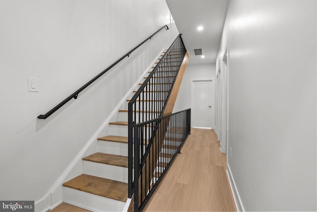 staircase with baseboards, visible vents, wood finished floors, and recessed lighting