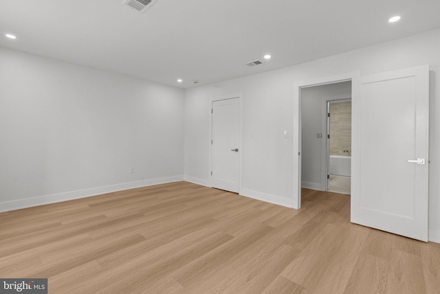 empty room featuring baseboards, light wood-type flooring, visible vents, and recessed lighting