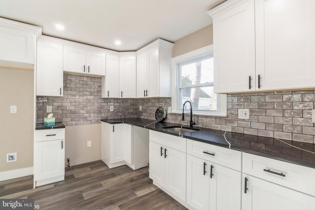 kitchen featuring tasteful backsplash, dark stone countertops, sink, and white cabinets