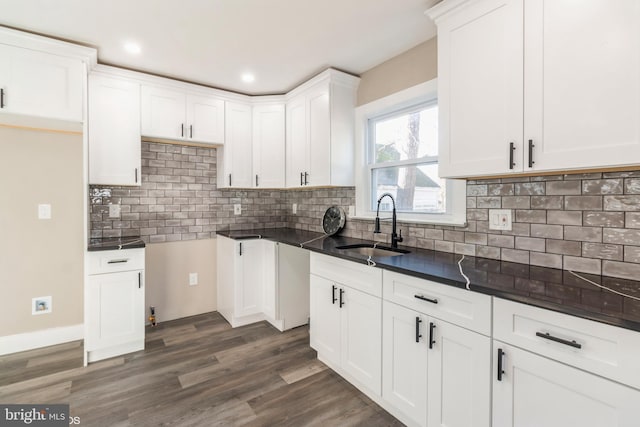 kitchen with decorative backsplash, white cabinetry, sink, and dark wood-type flooring