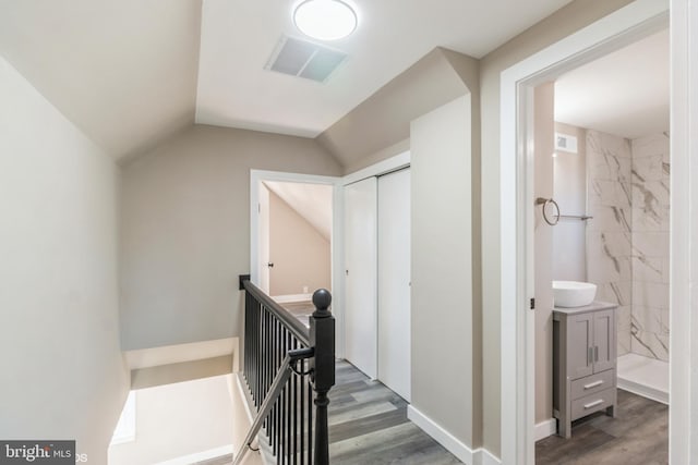 hallway with dark wood-type flooring and vaulted ceiling