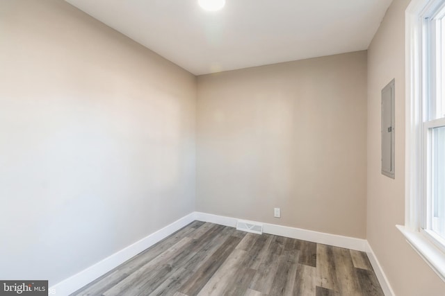 spare room with electric panel and hardwood / wood-style floors