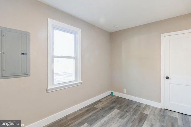 unfurnished room featuring electric panel, plenty of natural light, and hardwood / wood-style flooring