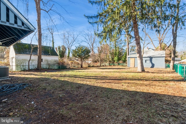 view of yard with a garage, an outbuilding, and central AC