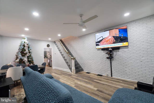 playroom featuring hardwood / wood-style flooring, ceiling fan, and brick wall