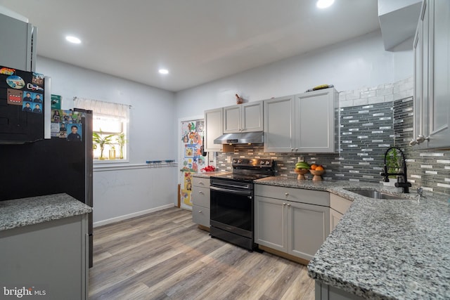 kitchen with gray cabinetry, sink, light stone counters, light hardwood / wood-style floors, and black appliances