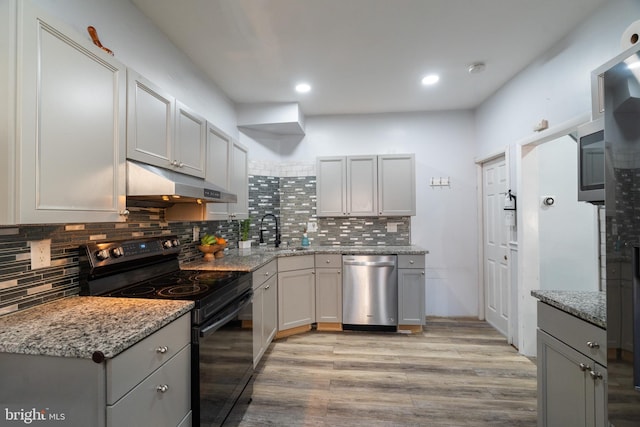 kitchen with sink, stainless steel dishwasher, black / electric stove, light hardwood / wood-style floors, and light stone counters