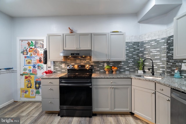 kitchen with sink, gray cabinets, light wood-type flooring, light stone counters, and stainless steel appliances