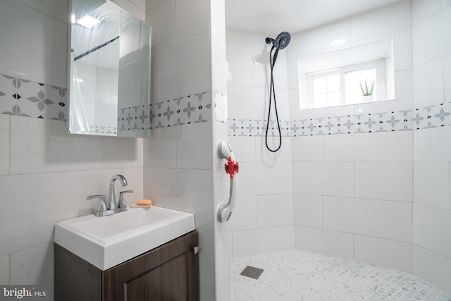 bathroom with tiled shower, vanity, tasteful backsplash, and tile walls