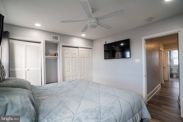 bedroom with ceiling fan, dark wood-type flooring, and multiple closets