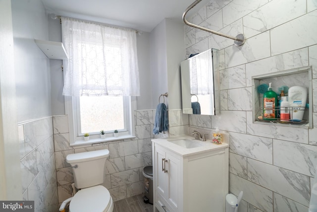 bathroom with vanity, toilet, and tile walls