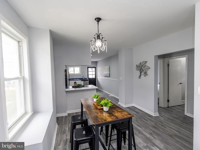 dining room with dark hardwood / wood-style flooring, plenty of natural light, and an inviting chandelier