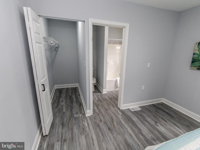 bedroom with dark hardwood / wood-style flooring, ensuite bath, and a closet