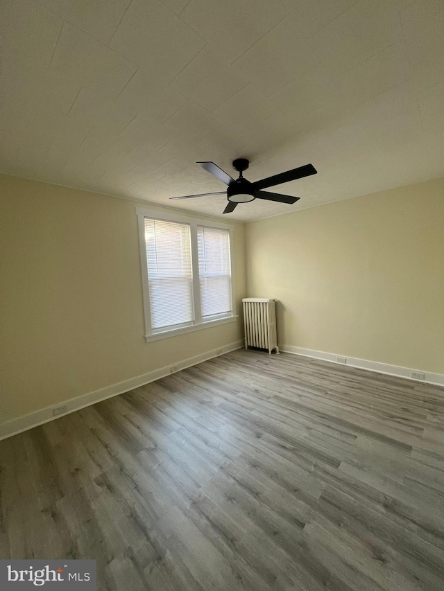 unfurnished room featuring ceiling fan, radiator, and light hardwood / wood-style flooring