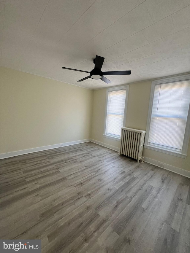 spare room featuring ceiling fan, light hardwood / wood-style flooring, and radiator heating unit