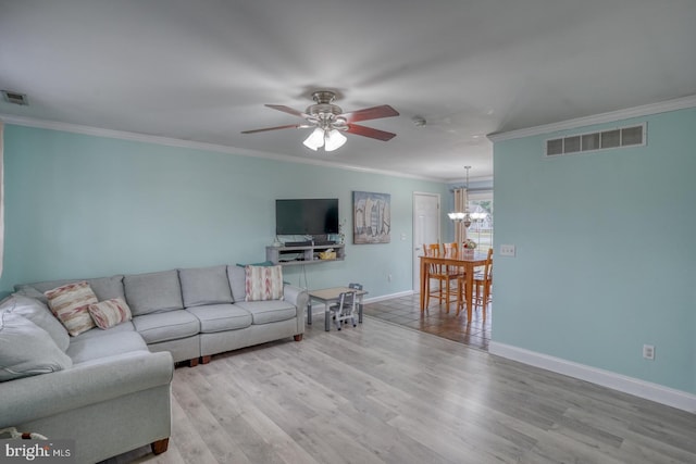 living room with light wood-type flooring, ceiling fan with notable chandelier, and ornamental molding