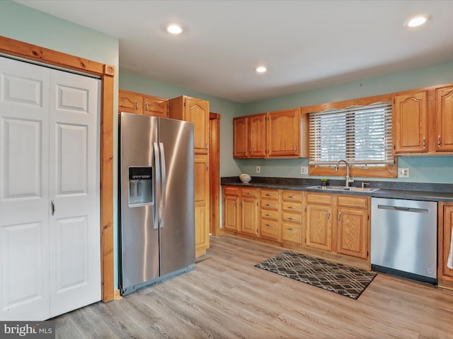 kitchen with appliances with stainless steel finishes, light hardwood / wood-style floors, and sink