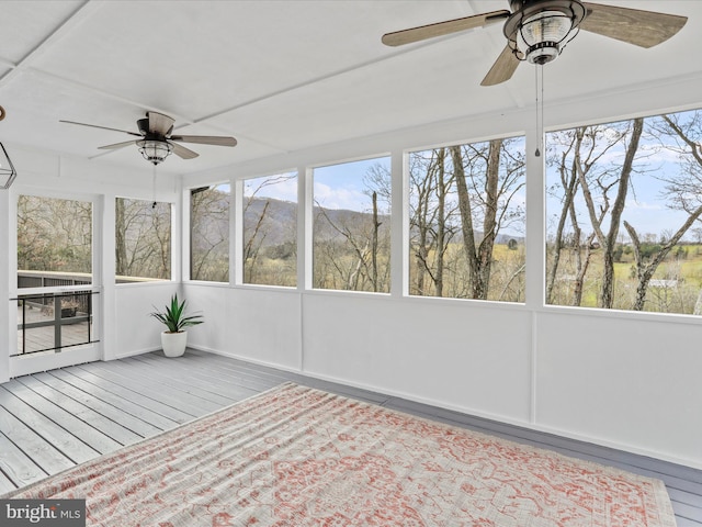 unfurnished sunroom featuring a mountain view and ceiling fan