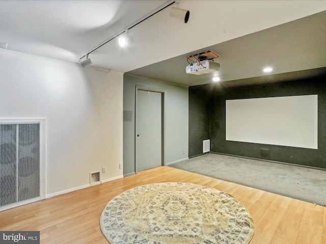 home theater room featuring hardwood / wood-style flooring and track lighting