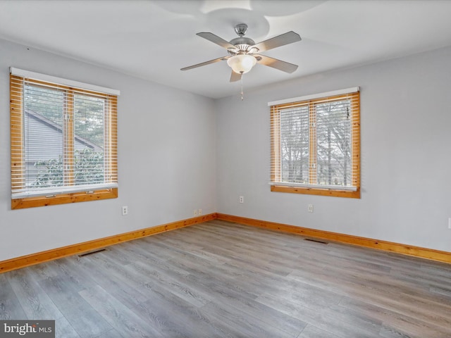 spare room featuring light wood-type flooring, plenty of natural light, and ceiling fan