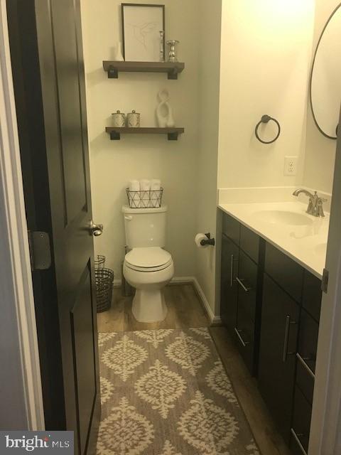 bathroom with toilet, vanity, and hardwood / wood-style flooring