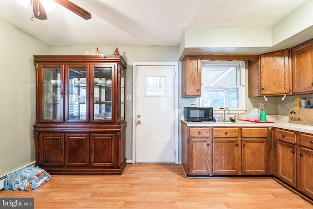 kitchen featuring ceiling fan, sink, light hardwood / wood-style floors, and a baseboard heating unit