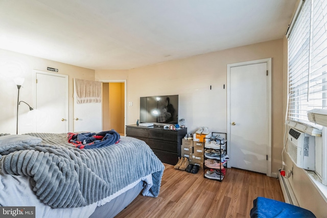 bedroom featuring cooling unit, a baseboard heating unit, and hardwood / wood-style flooring