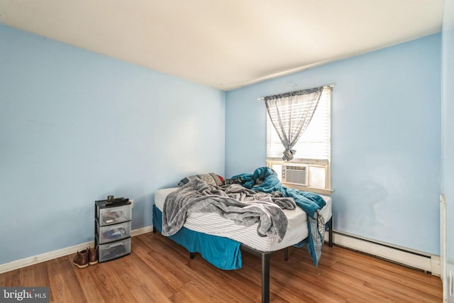 bedroom featuring hardwood / wood-style floors, cooling unit, and a baseboard heating unit