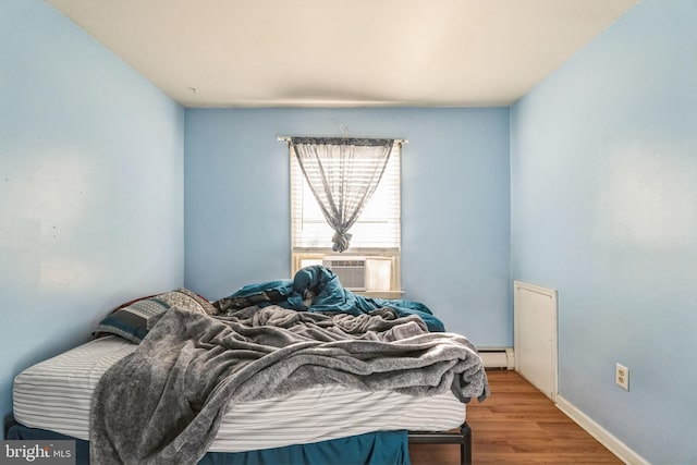 bedroom featuring hardwood / wood-style floors, cooling unit, and a baseboard radiator