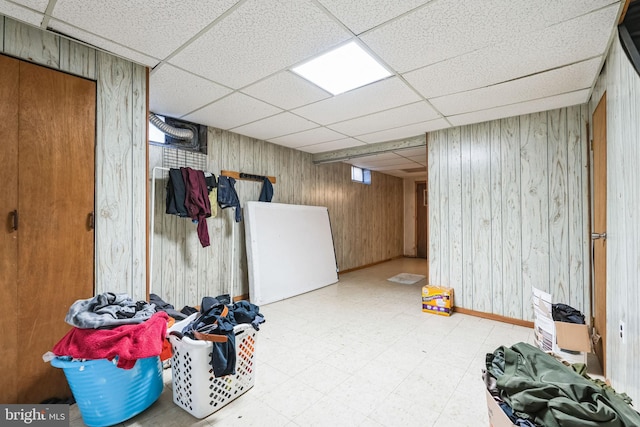 basement with a paneled ceiling and wood walls