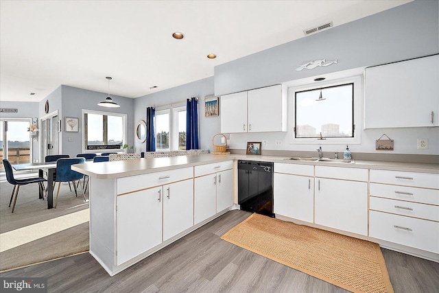 kitchen featuring kitchen peninsula, pendant lighting, black dishwasher, and white cabinets