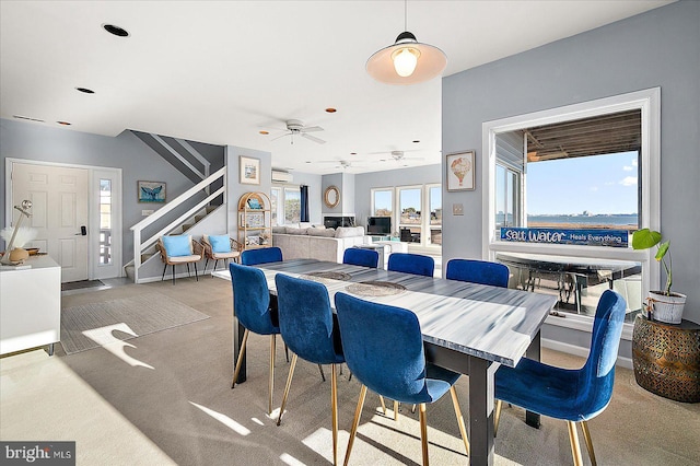 dining space with a wall mounted air conditioner, ceiling fan, and carpet