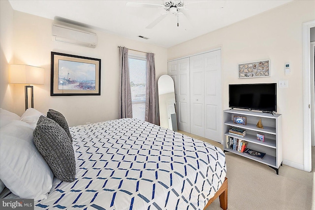 carpeted bedroom featuring a wall mounted air conditioner, ceiling fan, and a closet