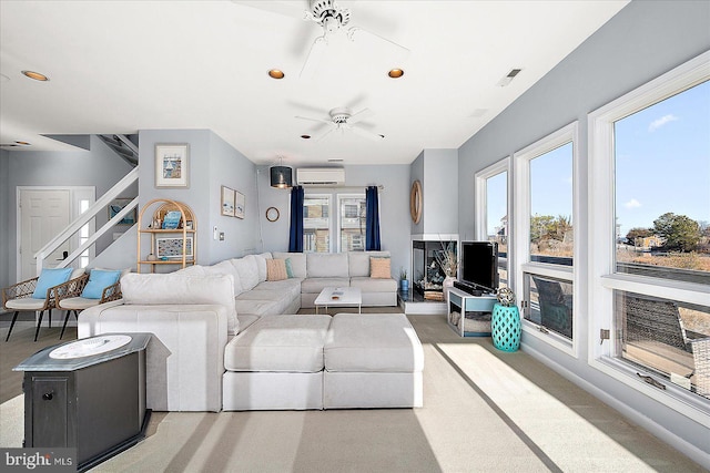 living room with built in features, a wall unit AC, and ceiling fan