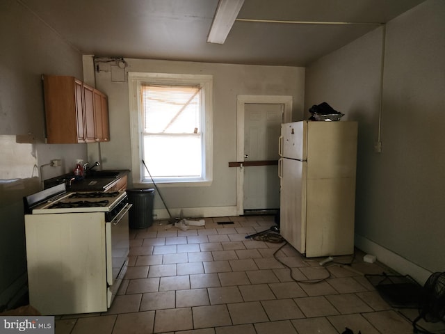 kitchen with white appliances, tile patterned floors, and sink