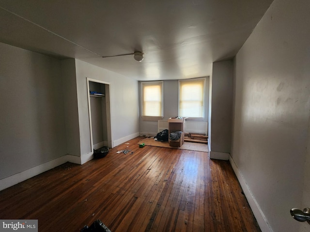 unfurnished bedroom featuring ceiling fan, a closet, and dark wood-type flooring