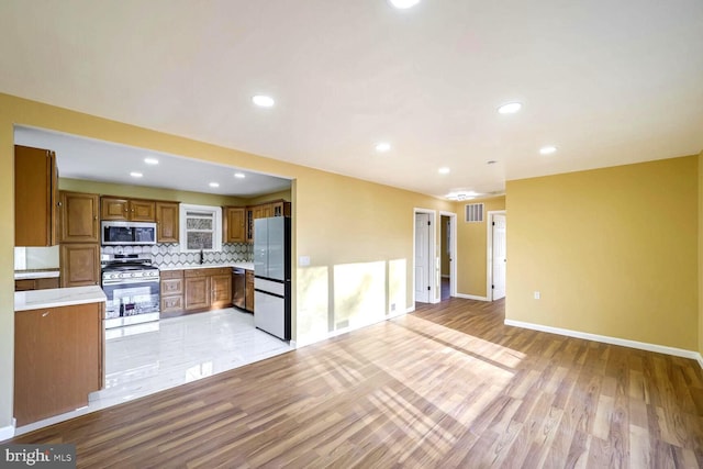 kitchen with light hardwood / wood-style floors, sink, stainless steel appliances, and tasteful backsplash